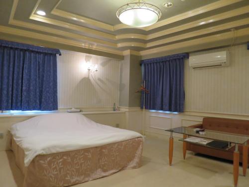 a bedroom with a bed and a table and blue curtains at Mio.ap in Toyoyama