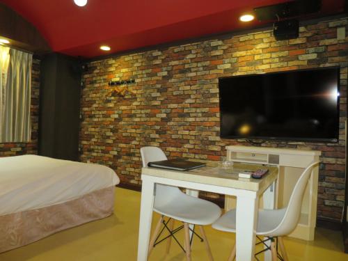 豊山にあるMio.apのベッド1台、テーブル、テレビが備わる客室です。