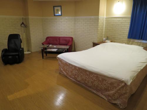a bedroom with a bed and a chair and a table at Mio.ap in Toyoyama