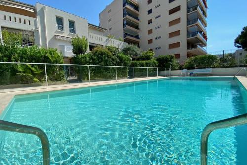 une grande piscine bleue en face de certains bâtiments dans l'établissement Appartement Basse Croisette - Welkeys, à Cannes