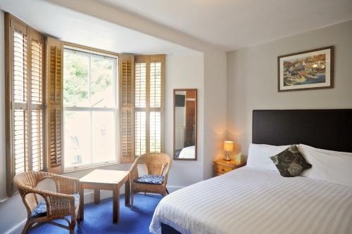 Penryn House Hotel في بولبيرو: غرفة نوم بسرير وطاولة وكراسي