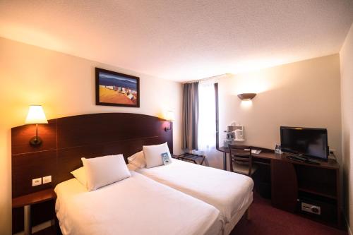 a hotel room with a large bed and a desk at Kyriad Chateauroux in Châteauroux