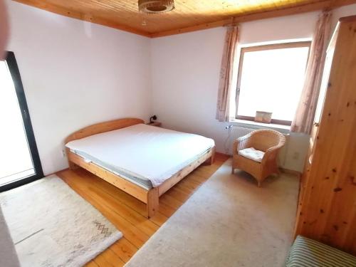 ein Schlafzimmer mit einem Bett und einem Stuhl sowie zwei Fenstern in der Unterkunft 95qm Wohnung Heyde in bester Wohnlage in Rostock
