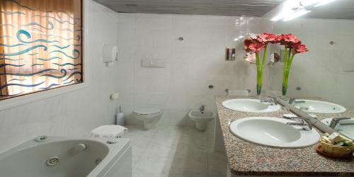 a bathroom with two sinks and a tub and a toilet at Valdenza Hotel in Campegine