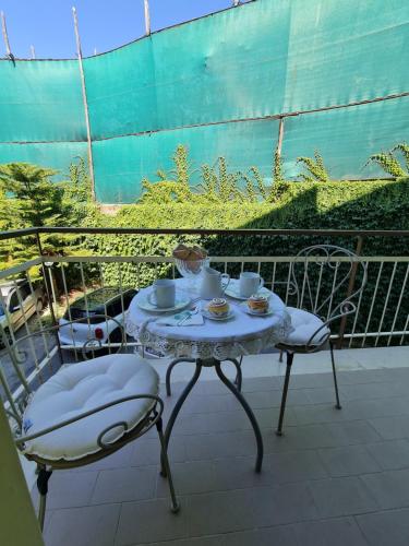 a table with two chairs and cups on a balcony at CASA ROSELLINA SORRENTO in Sorrento