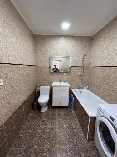 a bathroom with a toilet and a sink and a washing machine at Апартаменти в центрі Трускавця in Truskavets