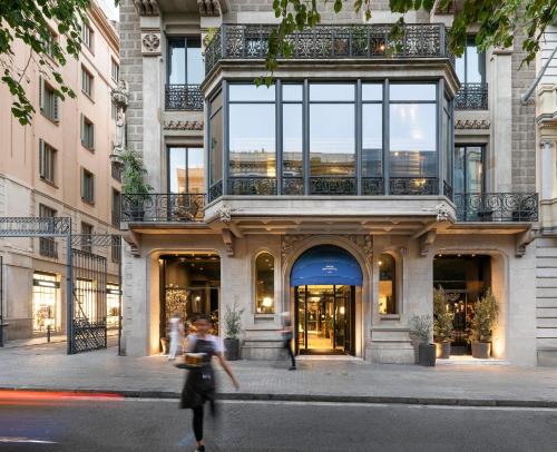 a woman walking down a street in front of a building at Hotel Casa Sagnier in Barcelona