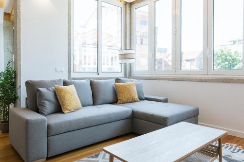 ein blaues Sofa im Wohnzimmer mit Fenstern in der Unterkunft ORM Prado Apartment in Porto