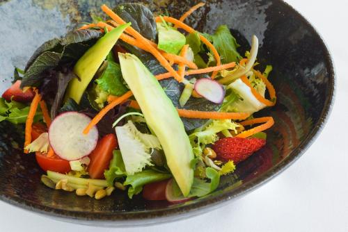 a salad in a black bowl with vegetables and strawberries at Torre del Marqués Hotel Spa & Winery - Small Luxury Hotels in Monroyo