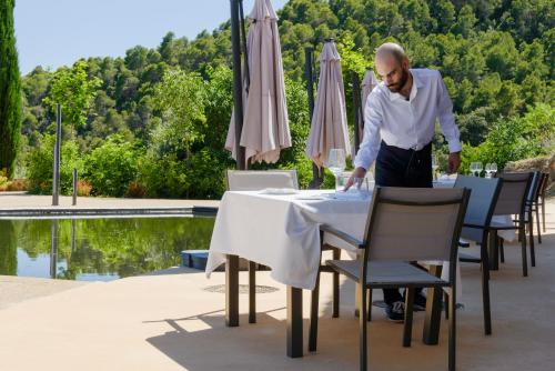 a man standing at a table in front of a pool at Torre del Marqués Hotel Spa & Winery - Small Luxury Hotels in Monroyo