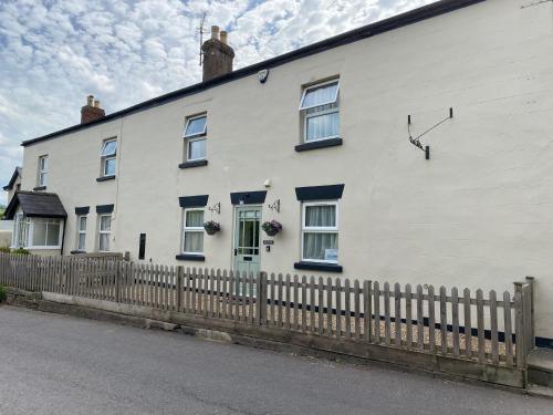 a white house with a fence in front of it at Jollys of Goodrich in Goodrich