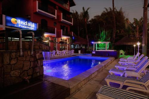 a pool with lounge chairs next to a building at Indaiá Praia Hotel in Bertioga