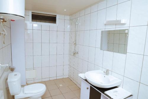 a white bathroom with a toilet and a sink at RESIDENCE OLIE OFFICIEL in Douala