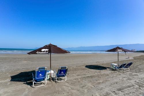 two chairs and an umbrella on a beach at Indaiá Praia Hotel in Bertioga