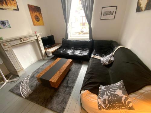 a living room with a black leather couch and a fireplace at Cozy studio close to Zaventem Airport in Brussels