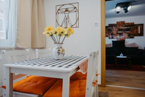 a white table with a vase of yellow flowers on it at Apartment RADO 75m2 mit Garten und Terrasse in Winden am See