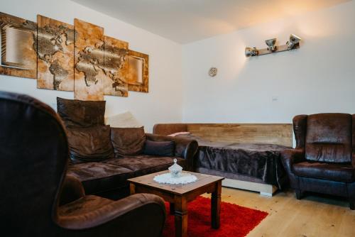 a living room with leather couches and a table at Apartment RADO 75m2 mit Garten und Terrasse in Winden am See