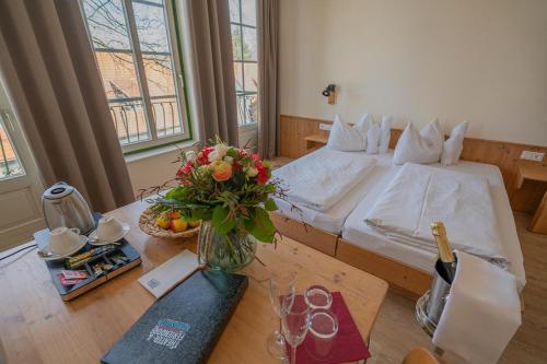 Un dormitorio con una cama y una mesa con un jarrón de flores en Theater- und Feriendorf Königsleitn GmbH en Litschau