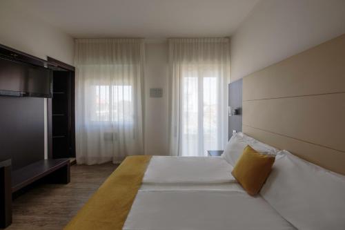 a hotel room with a large bed and a television at Hotel Bristol in Caorle