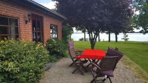 a table and chairs with a red table and a house at Sunrise in Tappernøje
