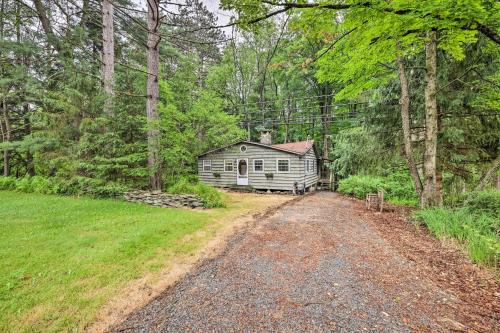 a house in the woods next to a dirt road at Trails and Creek On-Site Tranquil Greentown Cabin in Greentown