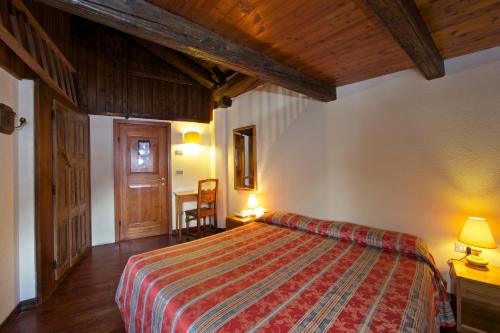 a bedroom with a bed in a room with wooden ceilings at Hotel Dolonne in Courmayeur