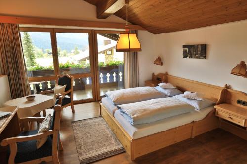 a bedroom with a bed and a desk and a window at Gästehaus Münchner Hof in Reit im Winkl