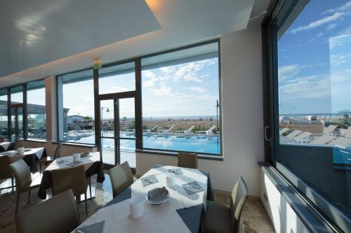 a restaurant with tables and chairs and a large window at Hotel Delle Nazioni - Adults Only in Caorle