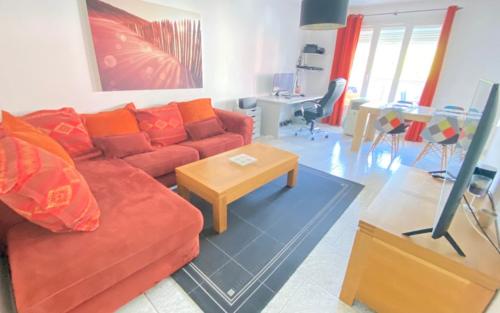 ein Wohnzimmer mit einem roten Sofa und einem Tisch in der Unterkunft Apt familial quartier Fontonne à Antibes by Weekome in Antibes