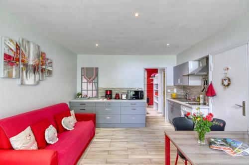 un salon avec un canapé rouge et une cuisine dans l'établissement Le Gîte les Châtaignes, à Volvic
