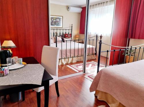 a bedroom with a bed and a dining table and a mirror at Canadian style house with 3D effect pool in Vinosady