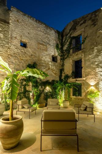 a patio with couches and a plant in front of a building at Isabella di Castiglia Apartments in Siracusa