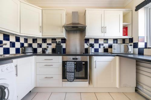 ブロードステアーズにあるOnyx Bay - Whole Apartment - WiFi - Beach - 2 Bed - Broadstairs Townの白いキャビネットと青と白のタイルが備わるキッチン