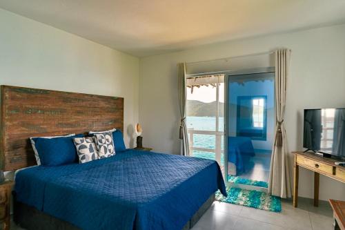 a bedroom with a blue bed and a sliding glass door at Casa Grega in Arraial do Cabo