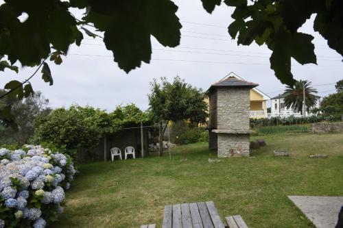 a yard with two white chairs and a stone fireplace at Casa Farruquitas in Cervo