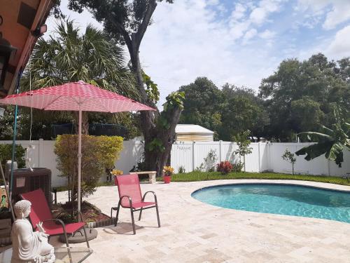 a patio with two chairs and an umbrella and a pool at Baynefamilyflorida. in Fort Lauderdale