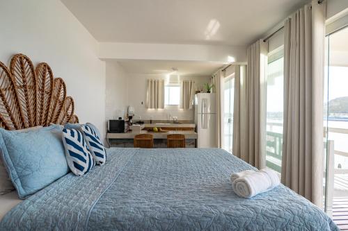 a bedroom with a blue bed and a kitchen at Loft Grécia In in Arraial do Cabo