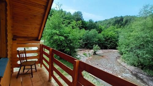 a porch of a cabin with a chair and a creek at Vikend kuća Đoković - Jahorina in Pale