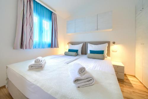 a bedroom with a white bed with towels on it at Holiday Homes Kanajt in Punat