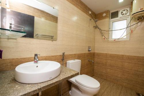 a bathroom with a sink and a toilet and a mirror at Ronnie's Studio Apartment in Saligao