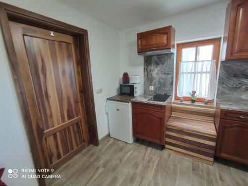 uma cozinha com armários de madeira, uma porta e um frigorífico em Éva Vendégház em Cserszegtomaj