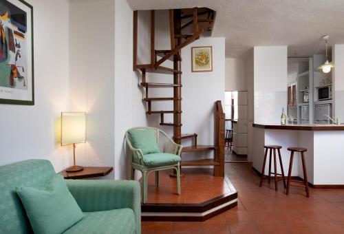 a living room with a green chair and a spiral staircase at Homey Experience - Marina Loft in La Maddalena