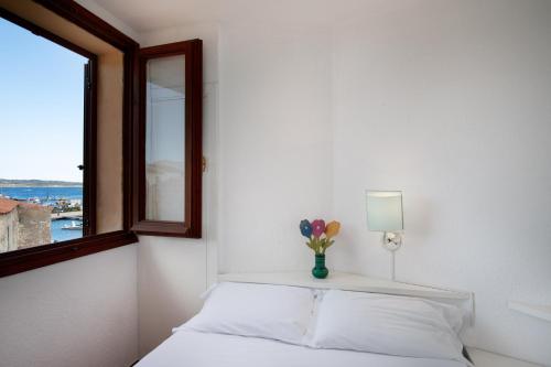 a bedroom with a bed with a window and a vase of flowers at Homey Experience - Marina Loft in La Maddalena