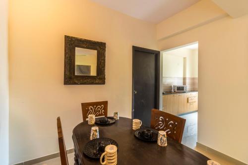 a dining room with a table and chairs and a mirror at Ronnie's Studio Apartment in Arpora