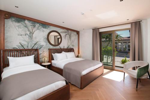 a bedroom with two beds and a mirror and a window at Genesis Hotel&Spa Alaçatı in Alaçatı