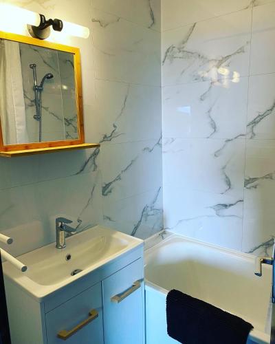 une salle de bain avec un lavabo, une baignoire et un miroir dans l'établissement Les Balcons d'Edelweiss, à Chamrousse