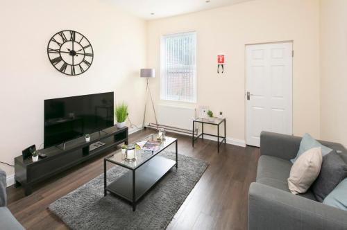 a living room with a couch and a tv at Coventry Large 4 Bedroom 4 Bath House Sleeps 4 Person Suitable for BHX NEC Solihull Rugby Warwick Contractors Ricoh Arena NHS Short & Long Business Stays Free Parking for 2 Vehicles, Close to City Centre High Speed Wifi in Coventry