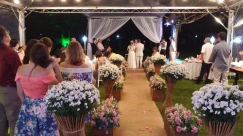 a group of people walking down a aisle with flowers at Indaiá Praia Hotel in Bertioga