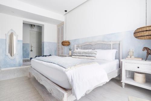 a white bedroom with a large bed and a mirror at Villa Bokeh Relais & Châteaux in Antigua Guatemala