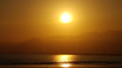 a sunset over the ocean with the sun in the sky at Indaiá Praia Hotel in Bertioga